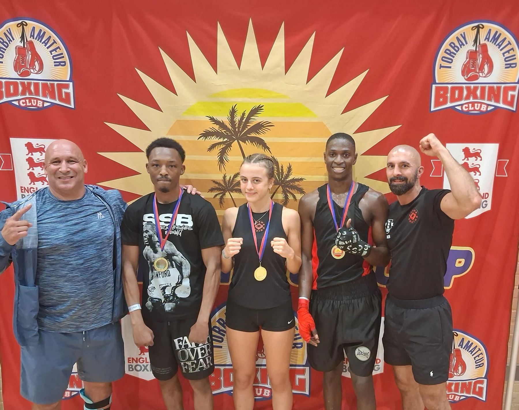 Arena boxers and coaches celebrating medals at the Torbay Amateur Boxing Club show